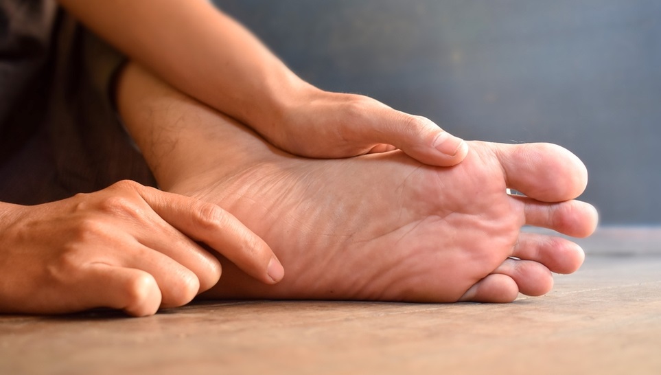 man holding his foot cause of tingling sensation