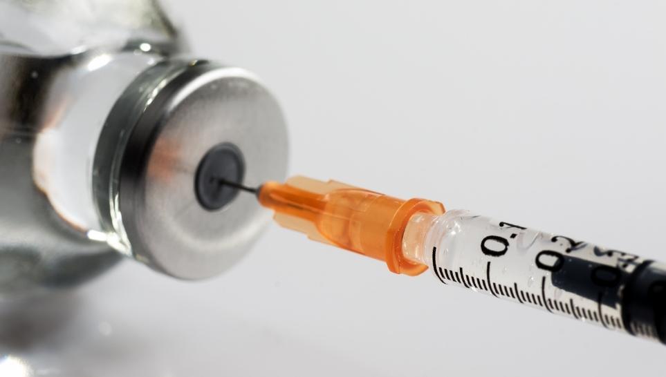 syringe getting a vaccine from a bottle