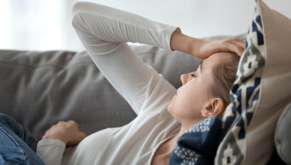 woman laying on a sofa feeling weak