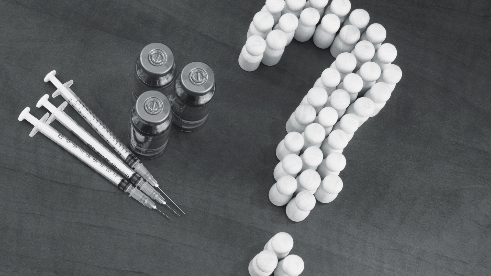 Crowd of people shaped as question mark, vaccine and syringes on wooden background.