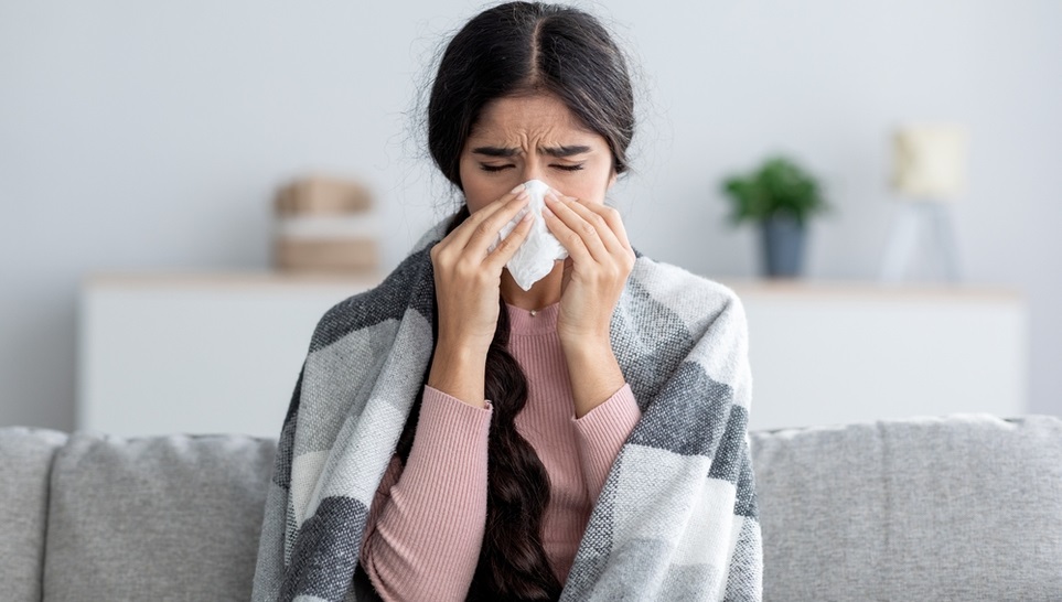 female having a fever sitting on a sofa