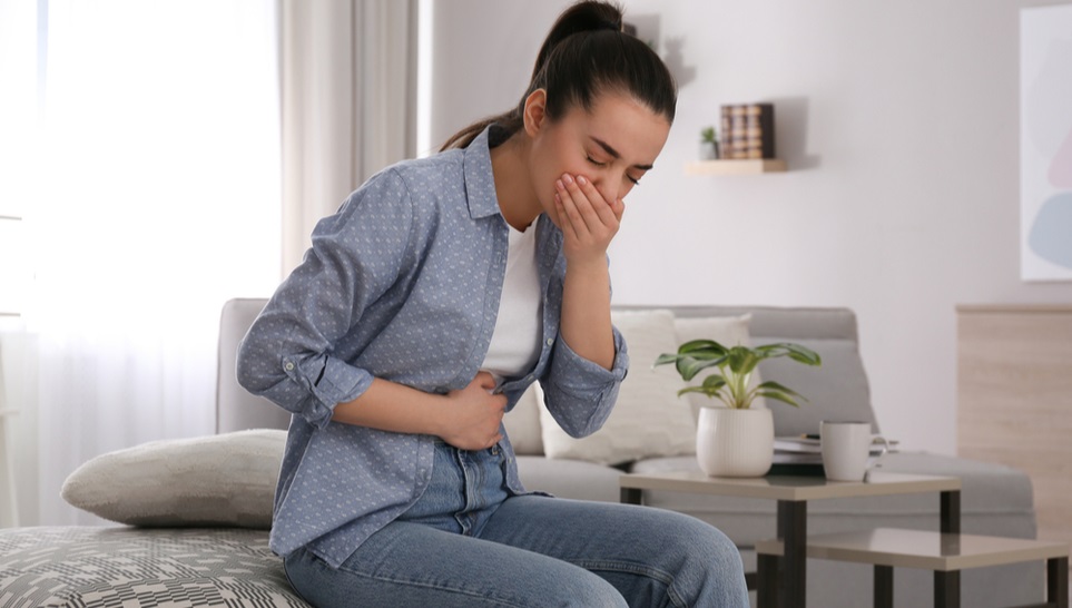 female suffering nausea while sitting on a couch