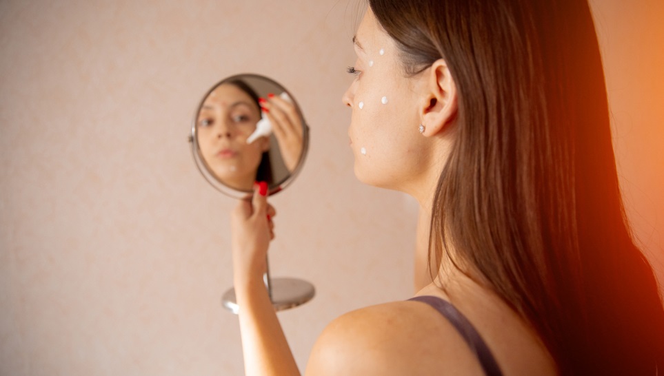 woman treating her chicken pox while looking on a mirror