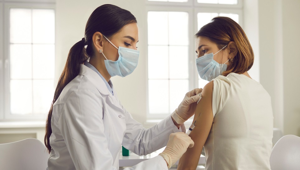 doctor injecting a vaccine to a woman patient