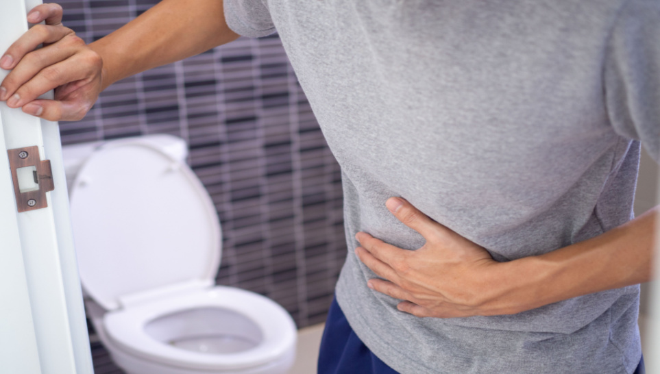 man standing holding his abdomen with upset stomach or diarhea after getting vaccinated