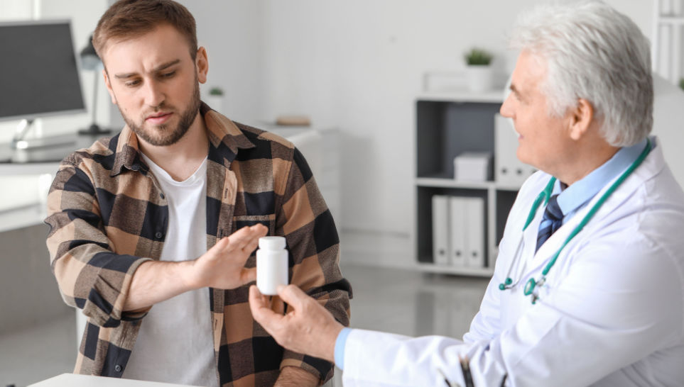 man refusing to take prescribed medicine from doctor