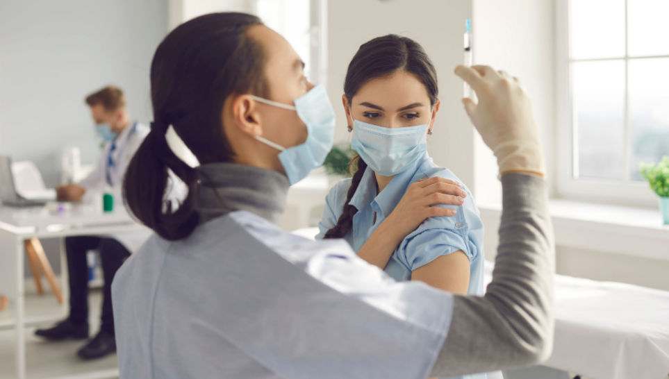 nurse preparing syringe to give a vaccine to a female patient