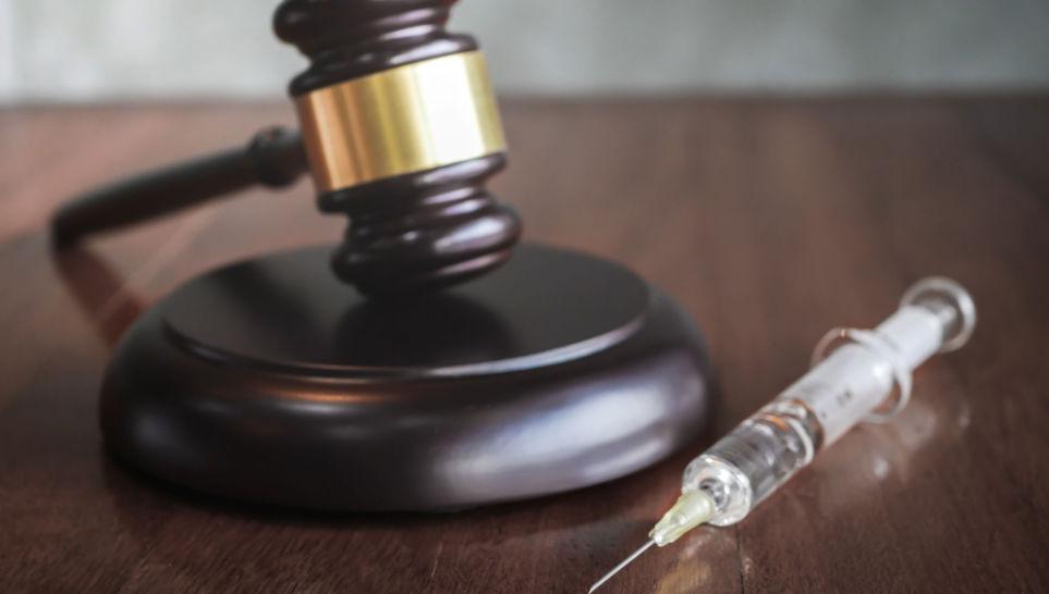 judges gavel and syringe injection on wooden table