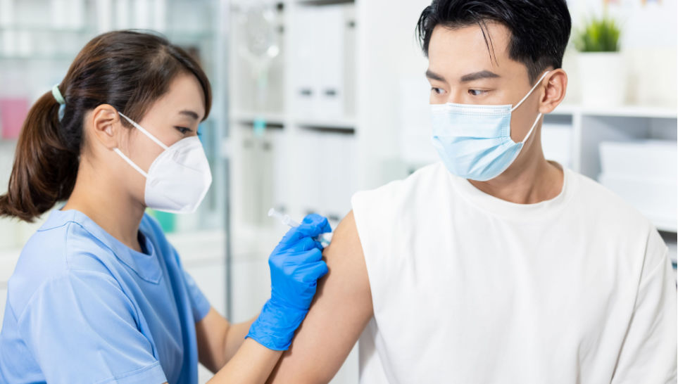 male patient wearing loose tshirt getting vaccine from female nurse