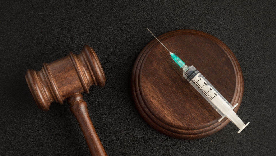 wooden gavel and syringe on black background