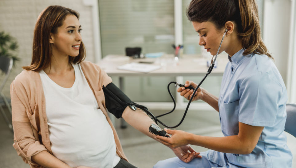 gynecology nurse checking blood pressure of pregnant woman