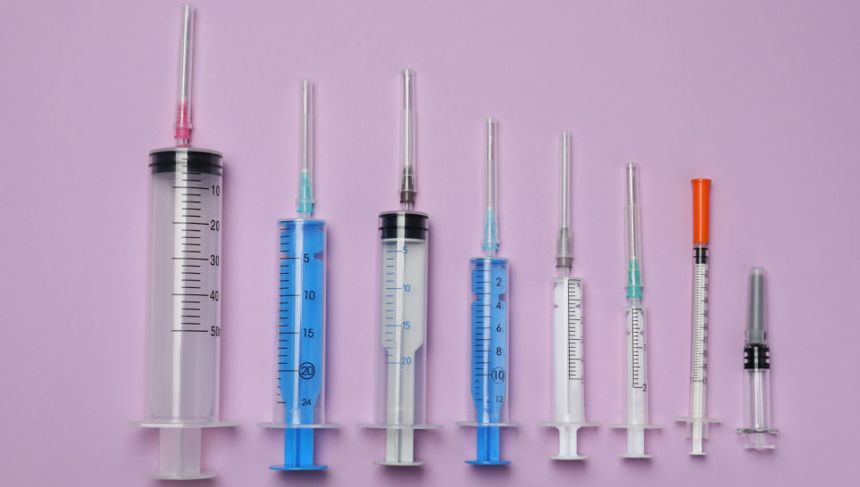 different size of syringe with needles on violet background