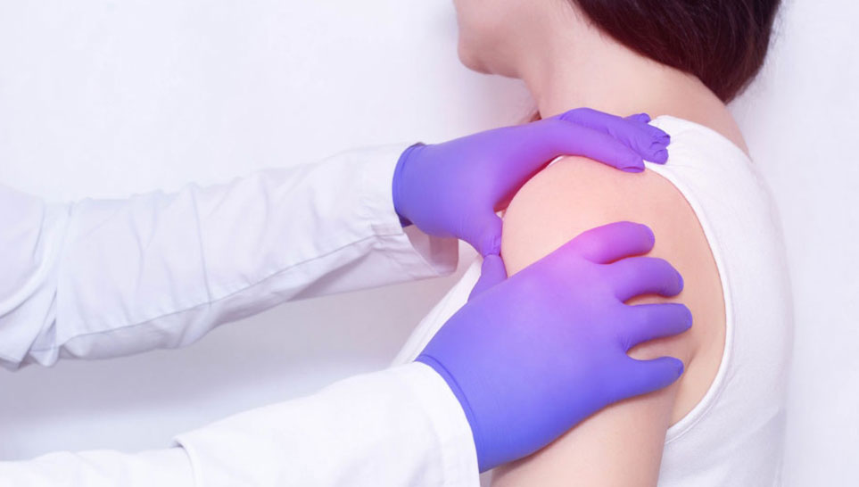 doctor examines sore shoulder of patient