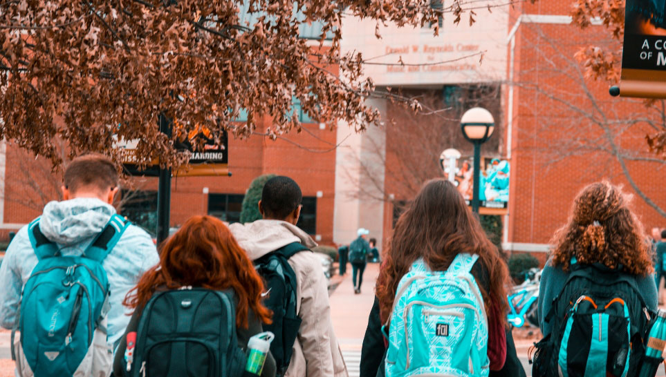 college students wearing backpacks going to school