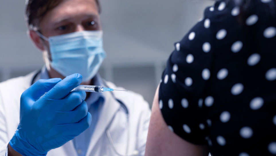 male doctor giving vaccine to teacher