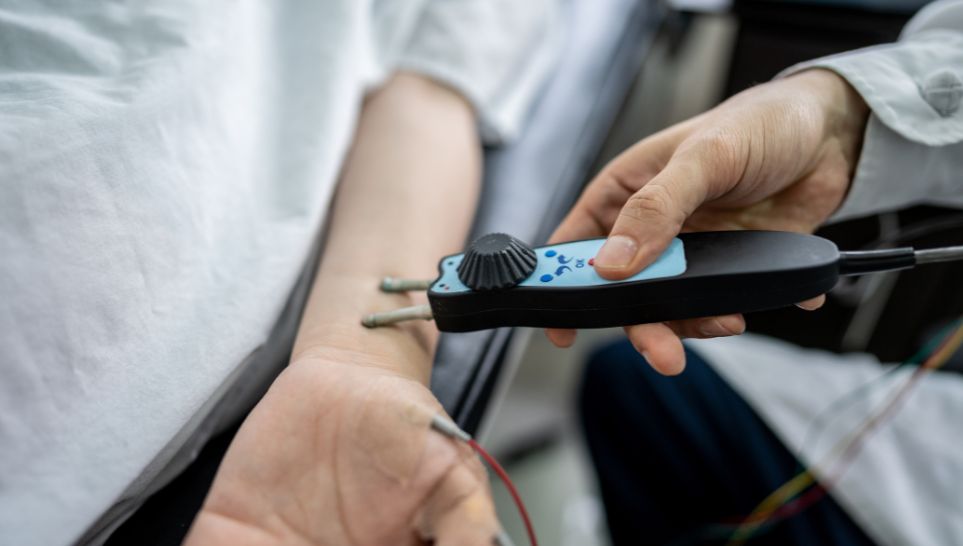 doctor using motor nerve conduction device on patient