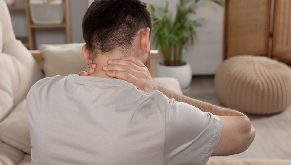 man suffering from neck pain in living room