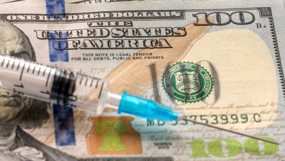 close up of syringe with injection on dollar banknotes