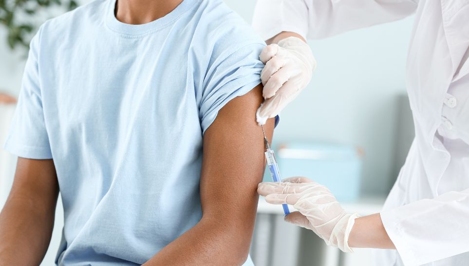 doctor vaccinating teenage high school student in clinic