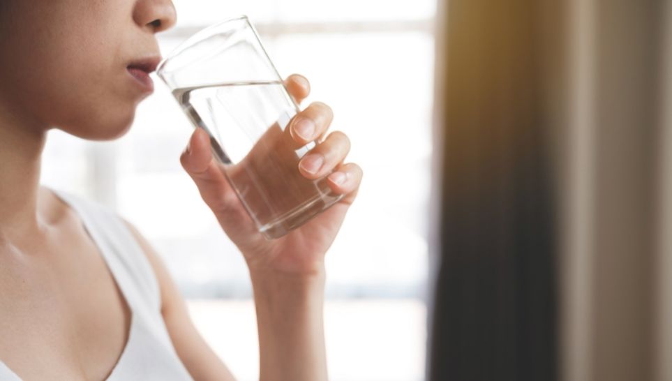 woman drinking a full glass of water