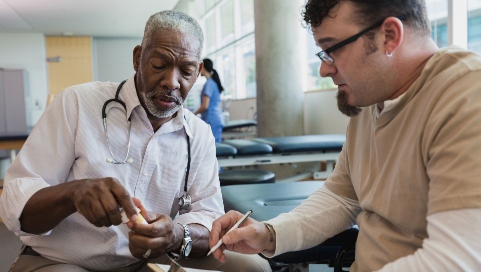 senior doctor explains drug interactions to male patient