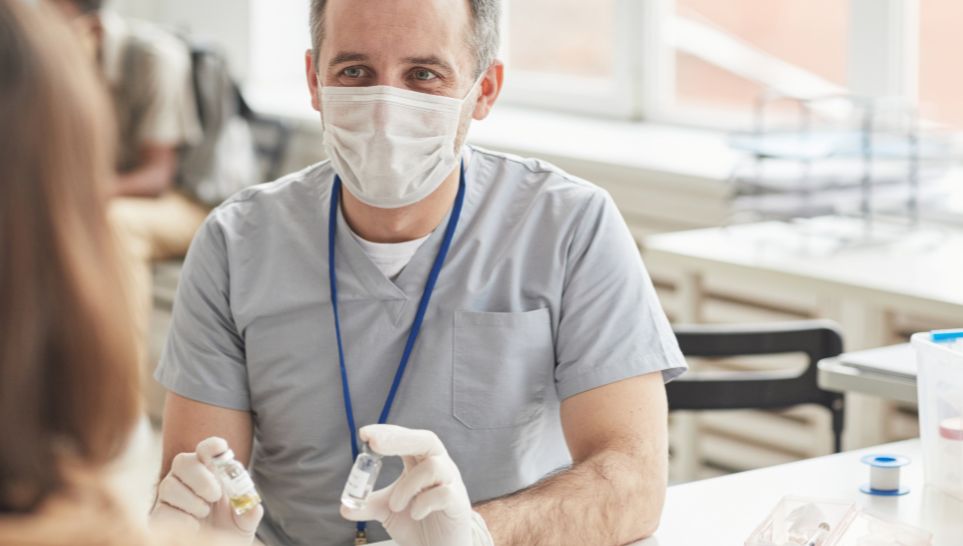 mature doctor consulting patients at vaccination center